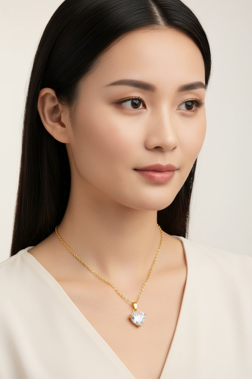Gold necklace with a heart-shaped crystal pendant on a white background